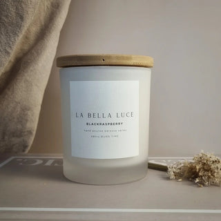 Frosted candle with wooden lid and 'La Bella Luce' label on a neutral background