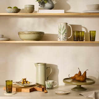 Shelves with ceramic bowls, mugs, and glasses on a neutral background