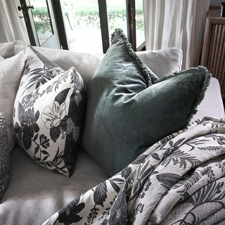 Gray sofa with floral-patterned pillows and a blanket in a cozy living room setting.