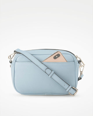 Light blue crossbody bag with a phone inside on a white background