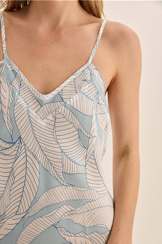 Close-up of a person wearing a patterned dress with thin straps on a beige background