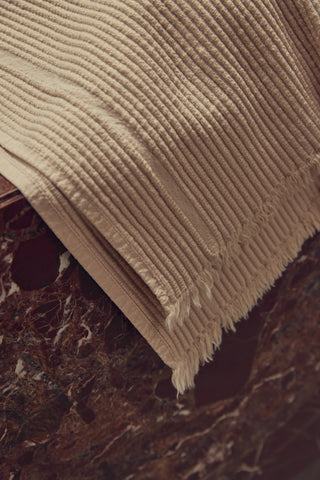 Beige textured blanket on a dark marble surface