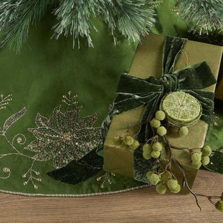 Green embroidered table runner with a gift and decorative elements on a wooden surface.