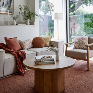 Living room with a beige sofa, armchair, wooden coffee table, and decorative items.