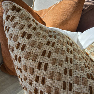 Close-up of woven textured pillow with brown and beige colors.