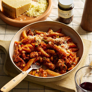 Penne pasta with tomato sauce in a bowl on a checkered tablecloth