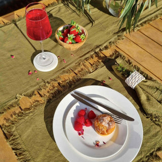 Dining setup with a plate of food, red wine, green napkin, and strawberries on a textured surface.