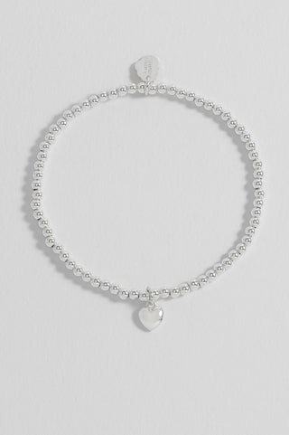 Silver bracelet with heart charm on a light gray background