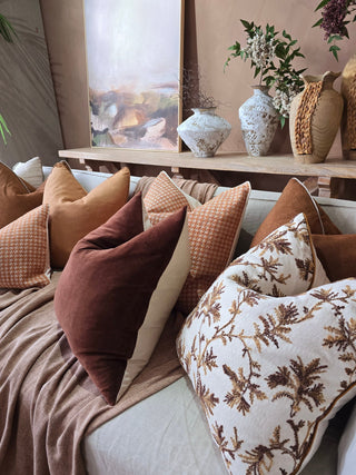 Cozy living room with pillows and decorative vases on a shelf.