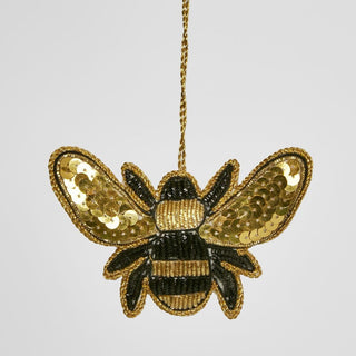 Gold and black sequin bee ornament on a gray background