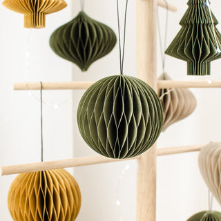 Decorative paper balls in green and yellow hanging on a wooden rack.