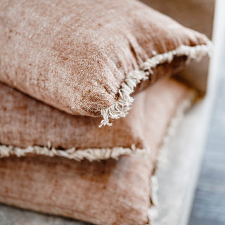 Stack of brown textured fabric pillows on a neutral background