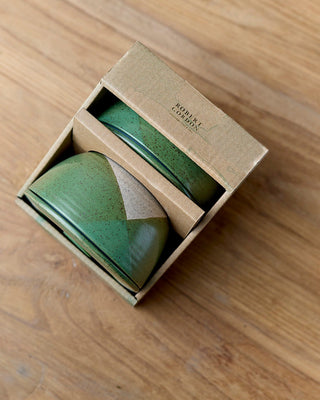 Green ceramic item in a box on a wooden surface