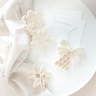Decorative paper flowers on a white surface with a light fabric background