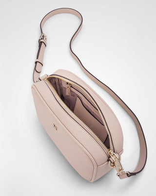 Pink crossbody bag with a gold zipper on a light gray background