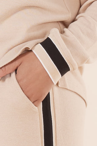 Close-up of beige jacket with black and white trim on sleeve