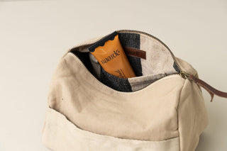 Beige toiletry bag with a visible brand name on a light background