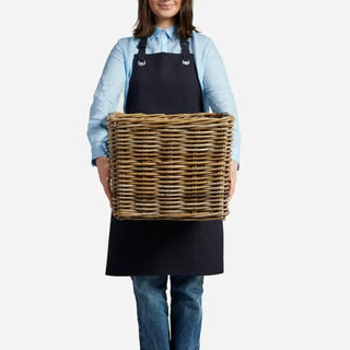 Person wearing a black apron holding a woven basket on a white background