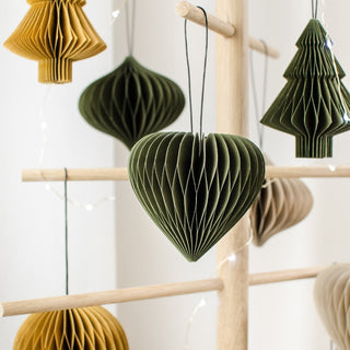 Heart-shaped paper ornaments in green and yellow hanging on a wooden rack.