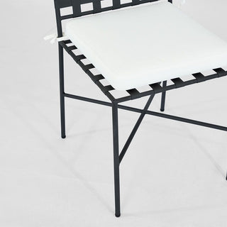 Black metal chair with white cushion on a light gray background