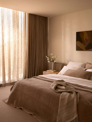 Cozy bedroom with a bed, curtains, and a painting on the wall.