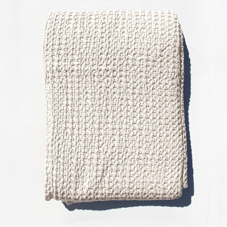 Folded beige textured blanket on a white background