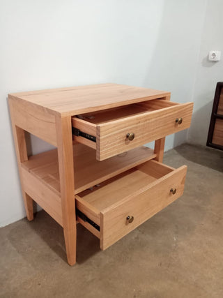 Wooden side table with two drawers against a white wall.