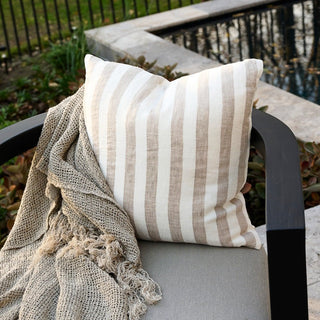 Striped pillow and textured blanket on a chair outdoors
