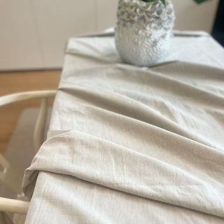 Beige tablecloth on a table with a decorative vase in the background