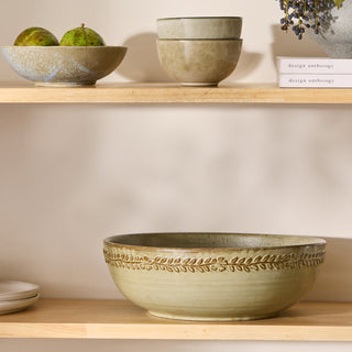 Set of ceramic bowls on wooden shelves with a neutral background