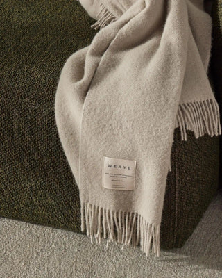 Gray scarf with 'WEAVE' label draped over a dark surface