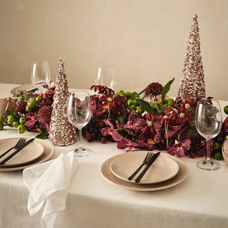 Decorative table setting with floral arrangements, wine glasses, and Christmas tree decorations.