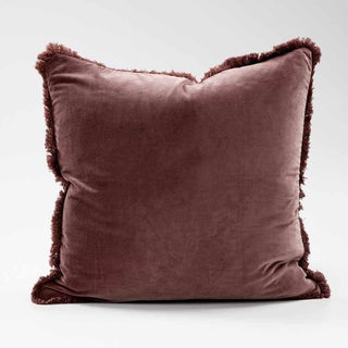 Brown velvet pillow with frayed edges on a white background