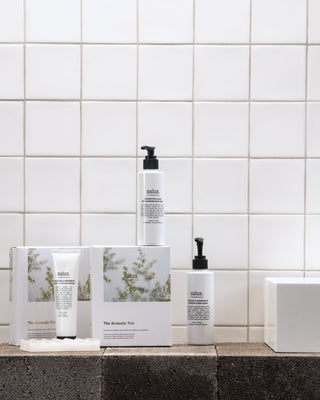Cosmetic bottles and boxes on a bathroom counter with tiled wall background