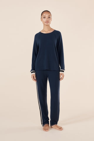 Person wearing navy blue pajama set with white stripes on a beige background