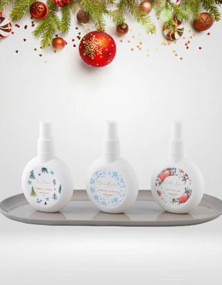 Set of white bottles with decorative labels on a gray tray, Christmas ornaments in the background.