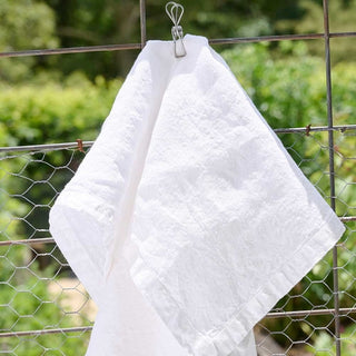 White towel hanging on a wire rack with a blurred green outdoor background