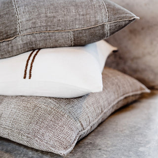 Stack of textured pillows in neutral colors on a soft surface
