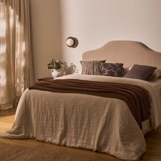 Neatly made bed with pillows and a blanket in a softly lit bedroom.