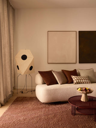 Modern living room with a beige sofa, decorative pillows, and a unique floor lamp.