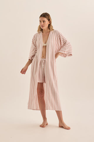 Woman wearing a pink striped robe and nightgown on a beige background