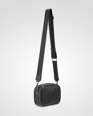 Black crossbody bag with a strap on a light gray background