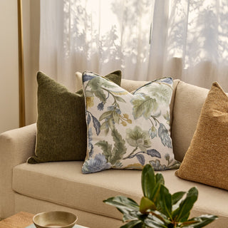 Decorative pillows on a beige sofa with a floral pillow in a living room setting.