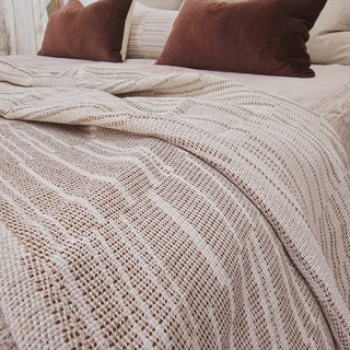 Textured beige blanket on a bed with brown pillows