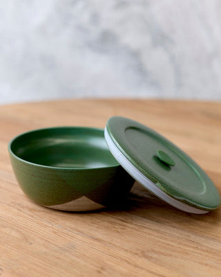 Green ceramic bowl with a matching lid on a wooden surface