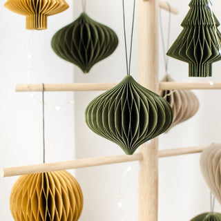 Decorative paper lanterns in green and brown hanging on a wooden rack.