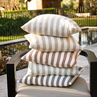 Stack of striped outdoor cushions on a chair with a garden background