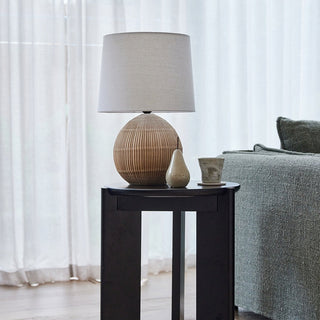 Table lamp on a side table next to a bed with a textured headboard.