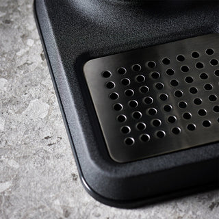 Black rubber mat with a grid pattern on a concrete surface
