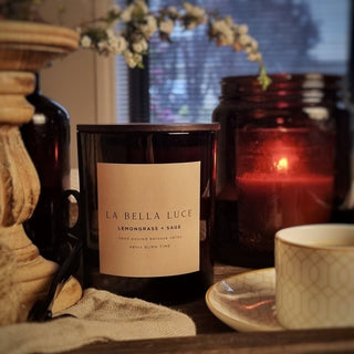 Candle labeled 'La Bella Luce' on a table with decorative items.